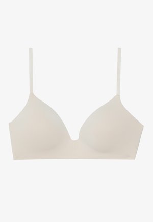 Light beige seamless bra with adjustable straps, featuring a V-shaped plunge neckline and smooth, stretchy fabric. No padding or embellishments.