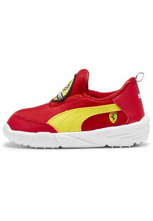 Scarpa slip-on in tessuto rosso con una striscia gialla, un ampio logo e una suola bianca con motivo antiscivolo.