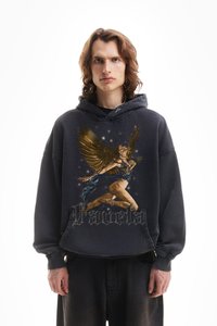 Μαύρη oversized φούτερ με κουκούλα, που απεικονίζει μια γραφική φιγούρα με φτερά και χρυσές λεπτομέρειες. Ο σχεδιασμός περιλαμβάνει αστέρια και τη λέξη "Pavela" σε καλλιγραφική γραμματοσειρά.