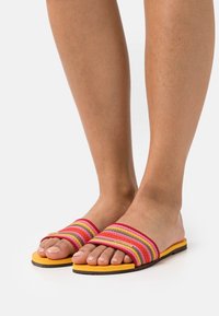 Randiga slidesandaler med en flerfärgad textilovandel i rosa, orange och gult, med en platt gummisula för komfort.