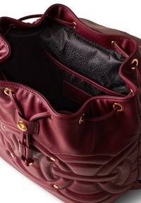 Burgundy leather bucket bag with a quilted design, golden hardware, and a black patterned interior. Drawstring closure with side pockets.