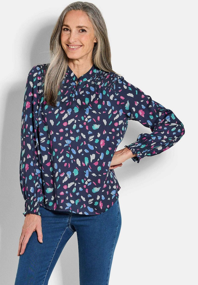 Blusa blu navy con un motivo astratto colorato, maniche lunghe con polsini elasticizzati e colletto con bottoni. Tessuto morbido con una vestibilità rilassata.