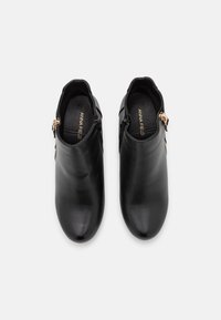 Botines de cuero negro con textura suave, puntas puntiagudas, cremalleras laterales y sutiles detalles en tono dorado.