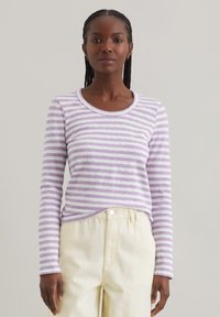 Langärmliges Shirt in Lavendel- und weißen Streifen, mit rundem Ausschnitt und weichem Griff. Kombiniert mit hellen, locker sitzenden Hosen.