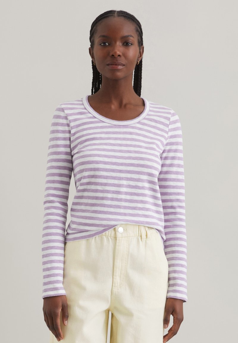 Langärmliges Shirt in Lavendel- und weißen Streifen, mit rundem Ausschnitt und weichem Griff. Kombiniert mit hellen, locker sitzenden Hosen.