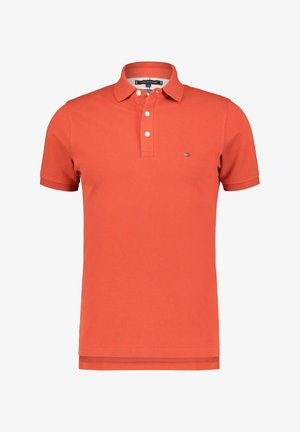 Orangefarbenes Polohemd mit kurzen Ärmeln, Kragen, drei weißen Knöpfen und kleinem Flaggen-Logo auf der linken Brust.