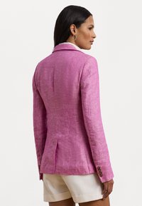 Rosa linneblazer med skräddarsydd silhuett, enkel vent och bruna knappar på ärmarna. Slät textur, lämplig för varma väderförhållanden.