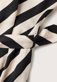 Černá a krémová diagonálně pruhovaná tkanina s malým černým sponou v pase, s hladkou texturou a lehkým designem.
