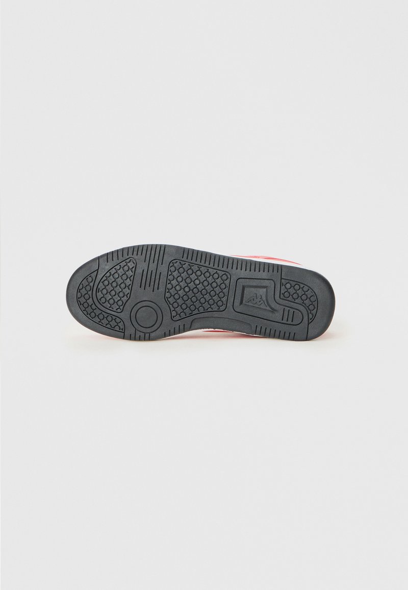 Suela de goma negra de un zapato con patrones de agarre texturizados y un logo, presentada sobre un fondo blanco liso.