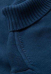 Marineblau gestrickter Stoff mit einem gerippten Kragen, der eine glatte Textur und nahtlose Nähte aufweist. Eine Nahaufnahme hebt die Handwerkskunst hervor.