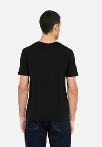 T-shirt nera con maniche corte, colletto rotondo, realizzata in tessuto di cotone. Texture liscia, senza motivi o accenti visibili, design semplice.