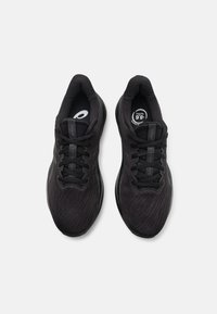 Baskets de sport noires avec une tige en maille texturée, des lacets plats et une semelle rembourrée. Présente des accents de logo et un design respirant.