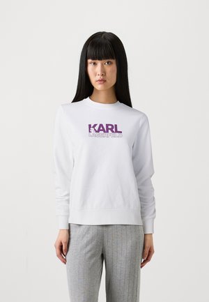 Baltas kokvilnas maisījuma džemperis ar izteiktu purpura krāsas "KARL LAGERFELD" logo uz krūtīm, ribotām piedurknēm un apakšmalu.