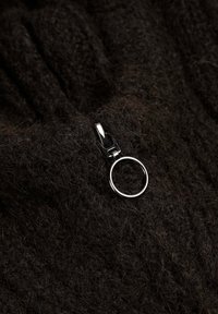 Tejido de punto marrón con un acabado suave y texturizado. Presenta un tirador de cremallera de metal plateado con un acento circular.