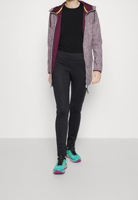 Hættejakke i kastanjefarvet med grå tekstur, lynlås; sort top; sorte leggings; løbesko i petrol og lilla med snørebånd.