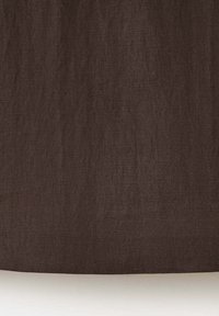 Gros plan d’un tissu marron texturé avec un motif de tissage diagonal subtil sur un fond neutre.