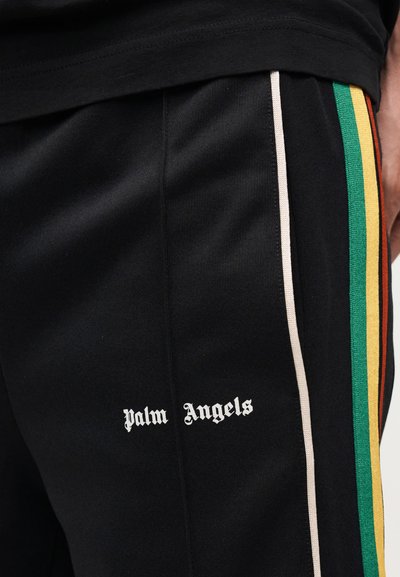 Μαύρο παντελόνι με λευκή επιγραφή «Palm Angels» και κάθετες ρίγες σε μπεζ, πράσινο, κίτρινο και πορτοκαλί κατά μήκος της πλαϊνής ραφής.