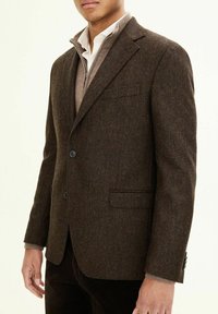Blazer a spina di pesce marrone realizzato in tessuto testurizzato, con design a un bottone, due bottoni e taschino sul petto.