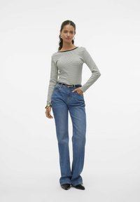 Gestreepte langemouwen top in zwart en wit. Hoog-waisted blauwe jeans met een rechte pijp. Zwarte schoenen. Eenvoudige accessoires, waaronder een riem.