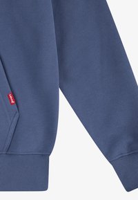Felpa blu scuro con orlo e polsini a coste, dotata di una piccola etichetta rossa del marchio Levi's sul lato e con una trama di tessuto liscia.