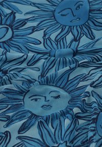 Blauwe stof met een zonnenpatroon. Het ontwerp bevat glimlachende zongezichten met knipogende uitdrukkingen en gestileerde stralen, in donkerblauw op een lichter blauwe achtergrond.