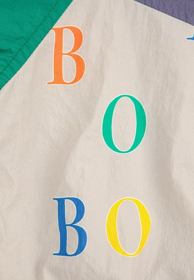 Lett stof med en glat tekstur, der har store, multicolore bogstaver (O, B) i orange, grøn, blå og gul mod en neutral baggrund.