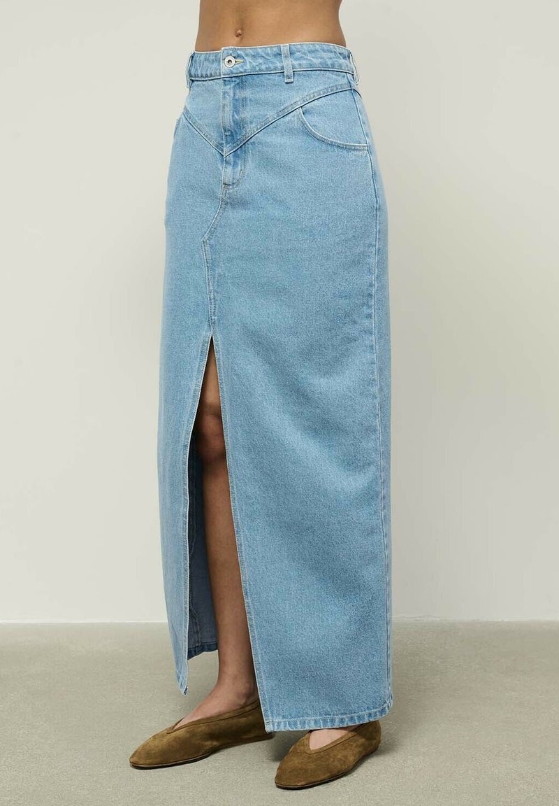 Šviesiai mėlyna džinsinė maksi sijonas su priekiniais įpjovimais, aukštu liemeniu ir vienu sagos uždarymu. Pasižymi šoninėmis kišenėmis ir tiesia siluetu.