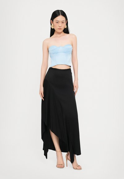 Top sin tirantes de color azul claro con detalles fruncidos, combinado con una falda maxi asimétrica negra de tejido elegante y sandalias de tacón alto beige.