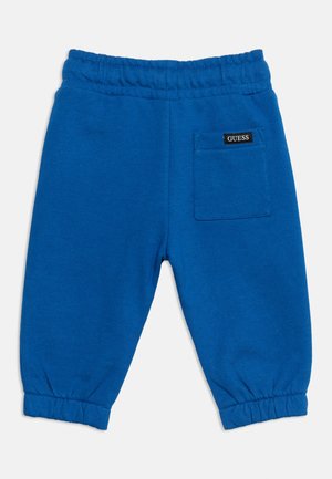 Pantalon bleu vif avec taille élastique et bas retroussés, doté d'une poche arrière avec une petite étiquette noire "GUESS".