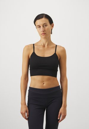 Zwarte geribbelde crop top met dunne bandjes, voorzien van een ronde halslijn en een aansluitend ontwerp, gecombineerd met donker aangesloten legging.