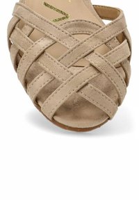 Sandalia de ante beige con un diseño trenzado y correas cruzadas, punta abierta y suela plana. Superficie texturizada con un interior suave.