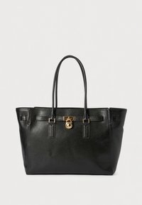 Sac fourre-tout en cuir noir avec deux poignées, ferrures dorées et détail de cadenas. Présente un design structuré et une surface texturée.