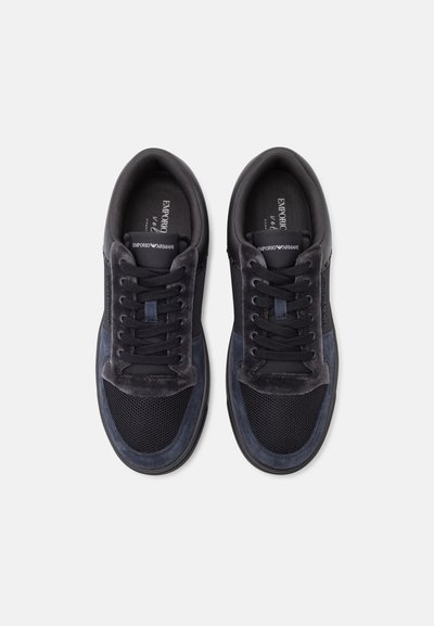 Paire de baskets noires et gris foncé Emporio Armani vues de dessus sur fond blanc, montrant les lacets et les détails en tissu maille.