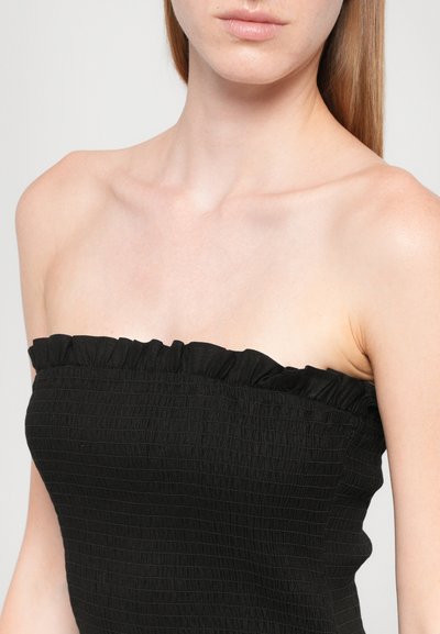 Juodas be petnešėlių viršus su rauktu kaklo iškirptės kraštu, pagamintas iš tekstūruotos, surinktos medžiagos ir aptemptos silueto linijos, pabrėžiančios viršutinę kūno dalį.