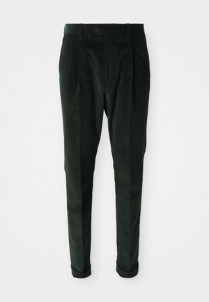 Dark green corduroy trousers with belt loops, front button, pleats, tapered legs, and cuffs on a white background.