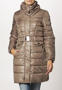 Brązowy, ocieplany płaszcz zimowy z wysokim kołnierzem, paskiem w talii oraz bocznymi kieszeniami na zamek. Posiada poziome przeszycia i błyszczącą fakturę.