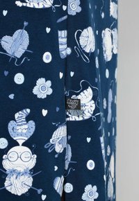 Tkanina w kolorze granatowym z jasnoniebieskimi ilustracjami kotów, włóczki, kwiatów, guzików i serc. Zawiera małą metkę z logo marki.