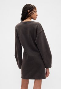 Didelis tamsiai pilkos spalvos medvilninis džemperio stiliaus suknelė. Ilgos rankovės, apvalus kaklo iškirpimas ir matomos siūlės apačioje bei rankogaliuose. Minkšta tekstūra.