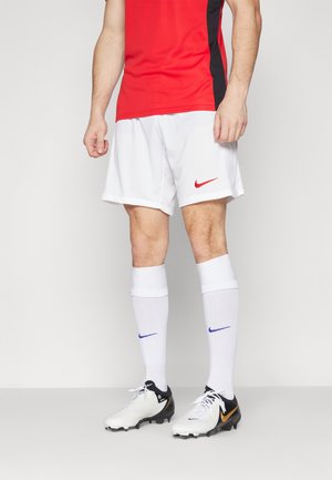 Rood en zwart shirt met korte mouwen, witte shorts met rood Nike-logo, witte sokken met blauw Nike-logo, zwart-witte voetbalschoenen.