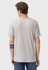 T-shirt grigia a maniche corte in una vestibilità rilassata, con scollo rotondo e una texture morbida, caratterizzata da dettagli di cucitura minimi sul retro.