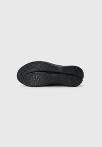 Zwarte sport schoenzool met een gestructureerd oppervlak met groeven en ronde patronen voor grip, gemaakt van rubber en synthetische materialen.