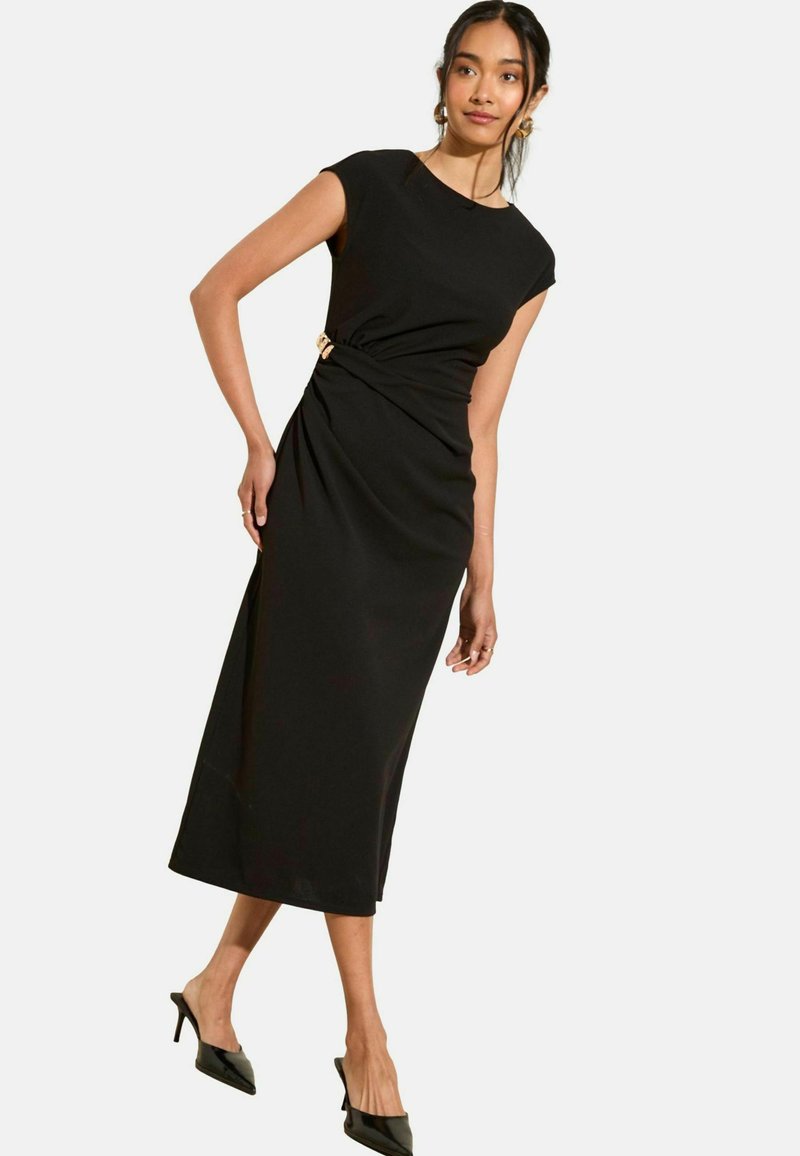 Schwarzes, knielanges Kleid mit tailliertem Oberteil und kurzen Ärmeln, das ein gedrehtes Design an der Taille und einen goldenen Akzent aufweist. Glatte Textur.
