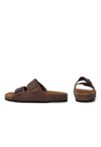 Brown faux leather slide sandals with two adjustable buckles, cork footbed, and textured rubber outsole. Flat, open-toe design.