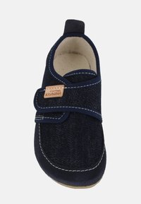 Scarpa da bambino blu navy realizzata in denim con una fascia in velcro, cuciture bianche a contrasto e un'etichetta con il marchio sul lato.