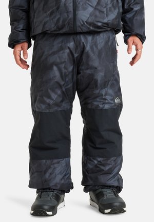 Water-resistant snow pants in dark gray with a textured pattern, contrasting black lower panels, elastic cuffs, and a logo on the leg.