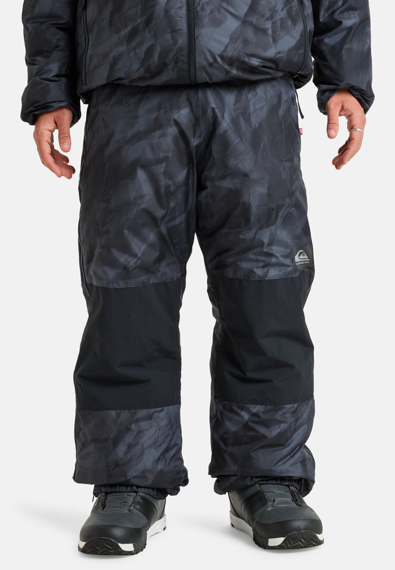 Wasserabweisende Schneehose in Dunkelgrau mit strukturiertem Muster, kontrastierenden schwarzen unteren Paneelen, elastischen Bündchen und einem Logo am Bein.