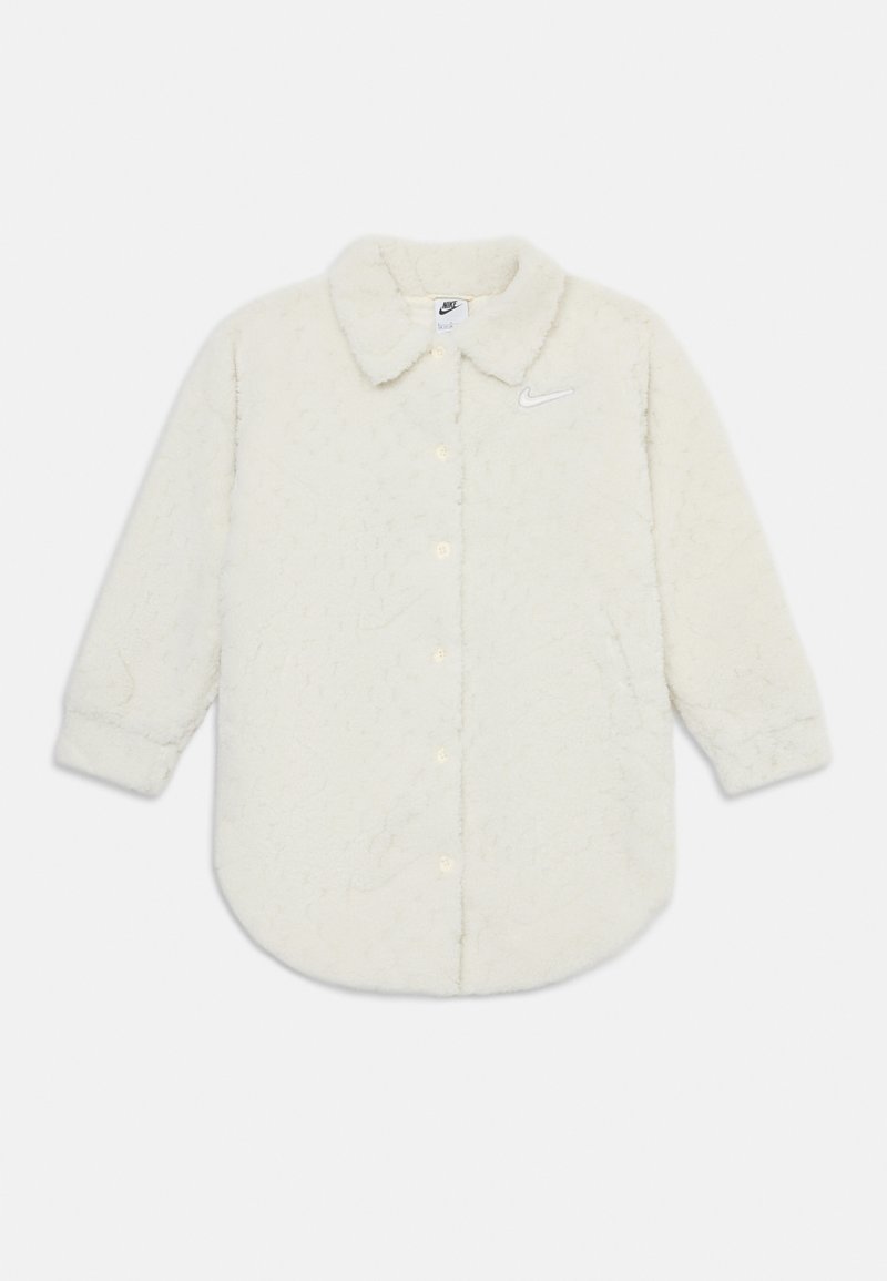 Balts villaines pogu krekliņš ar apkakli, kas izceļas ar teksturētu rakstu un mazu Nike logo kreisajā krūtī.