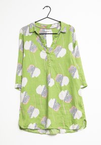 Grøn tunika med trekvartærmer, der har et blomstermotiv i hvide og sorte prikker, med V-hals og let tekstur.
