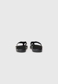 Zwarte flip-flop sandalen met gestructureerde stoffen banden. Gevoerde, platte zool met een matte afwerking. Eenvoudig ontwerp, zonder verdere versieringen.