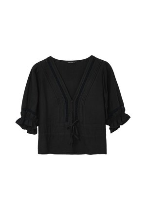 Blouse noire en tissu texturé. Caractérisée par un décolleté en V, des manches volantées et des tresses décoratives le long de l'encolure et du centre. Détail à nouer à la taille.
